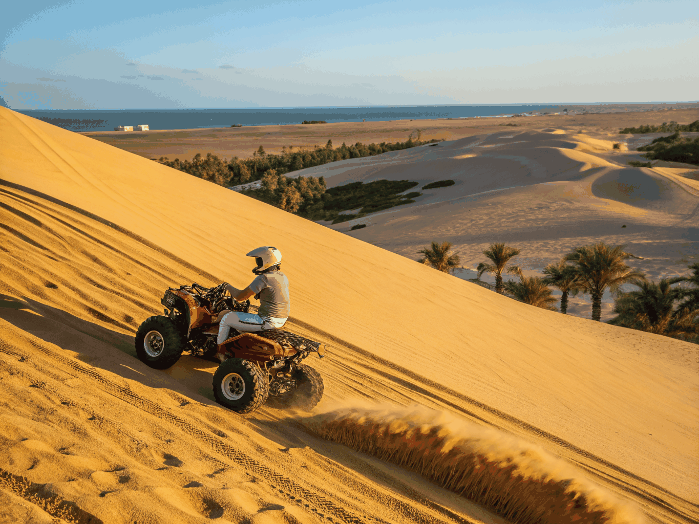 Tourist driving a quad bike across red desert dunes