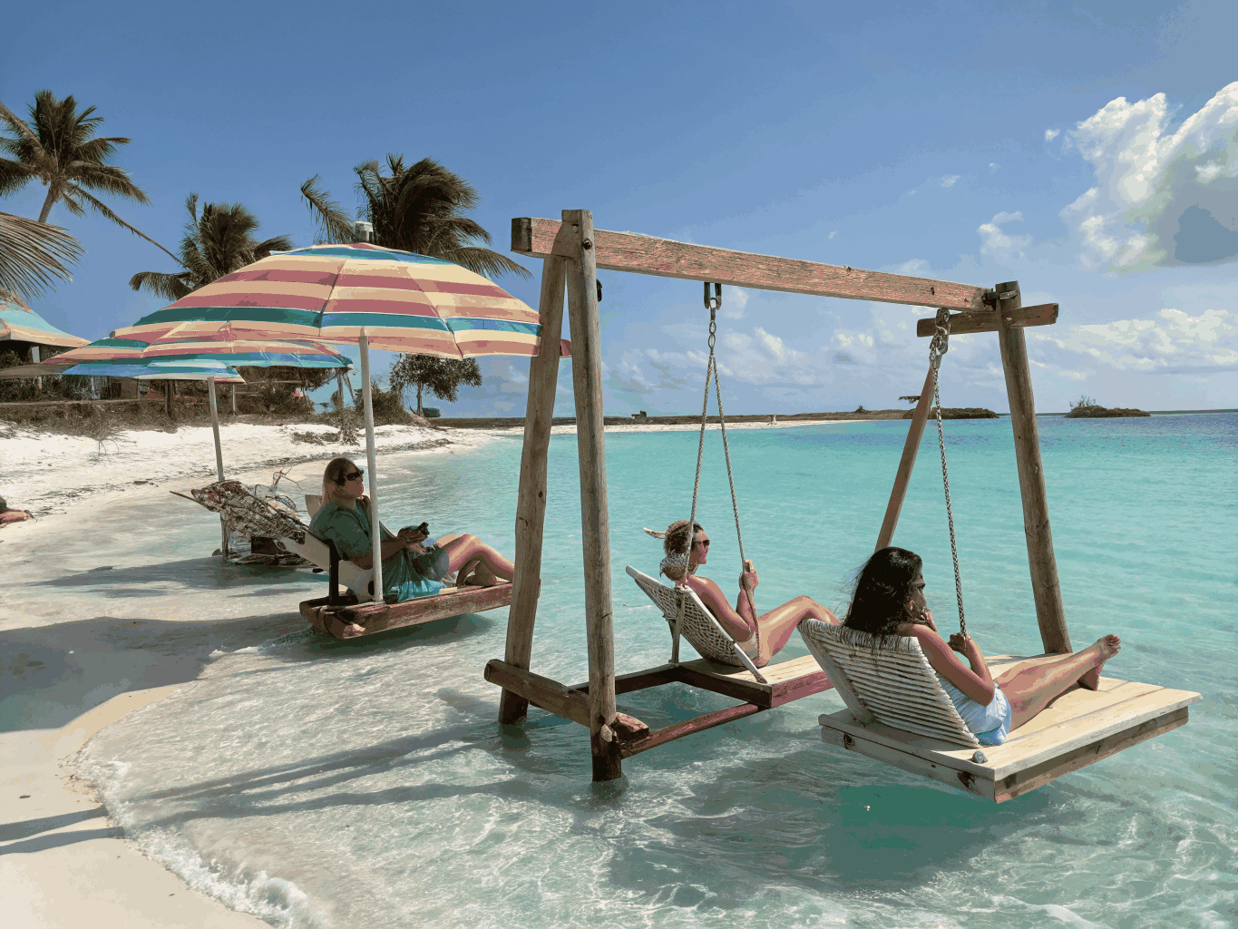 Sunny Red Sea island sandbar with wooden swings and turquoise water at Orange Bay